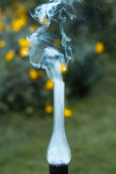 Uma velha lâmpada de querosene fumante em uma grama verde . — Fotografia de Stock
