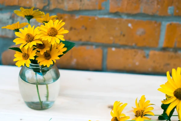 Arka plan bulanık ile ahşap bir masaya sarı çiçek.