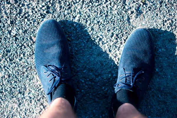 Men's legs in blue shoes on the asphalt. Royalty Free Stock Photos