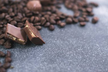 Kahve çekirdekleri ve fayans mat koyu arka plan üzerinde koyu çikolata.