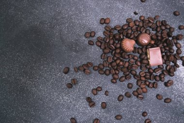 Kahve çekirdekleri ve fayans mat koyu arka plan üzerinde koyu çikolata.