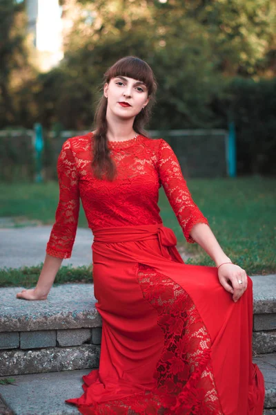 Adımlar üzerinde uzun elbiseli güzel genç kız oturur.