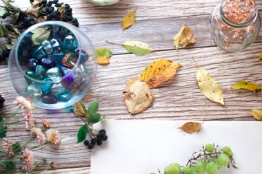 Cam Kavanoz ahşap sonbahar arka plan üzerinde çok renkli taşlarla.