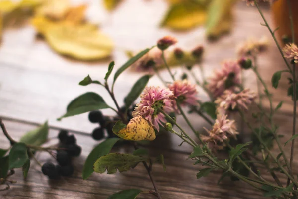 Gedroogde bloemen met Herfstbladeren op een houten achtergrond. — Stockfoto