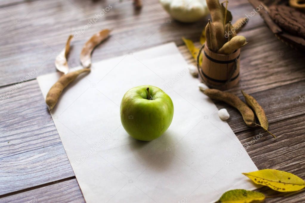 A green apple on a white sheet on a wooden background.