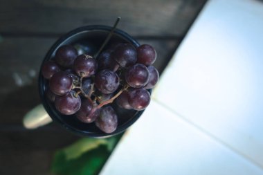 Bir avuç üzüm beyaz bir kupa.