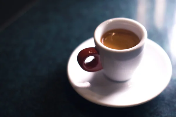 Una taza de café es americano sobre un fondo oscuro . — Foto de Stock