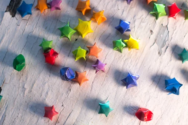 Multicolored paper stars on a wooden white background. — Stock Photo, Image