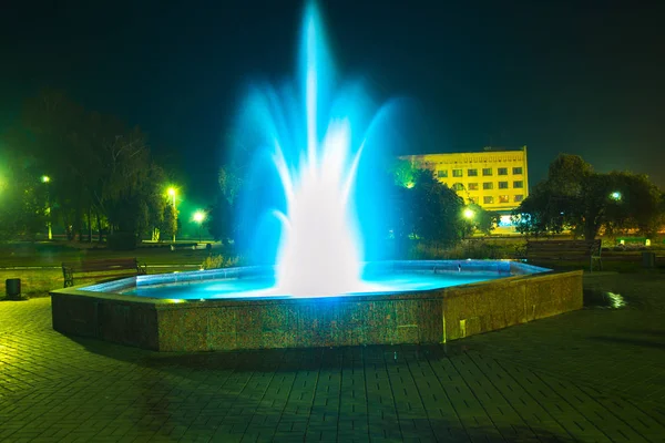 Fuente iluminada por la noche en un pequeño pueblo . —  Fotos de Stock