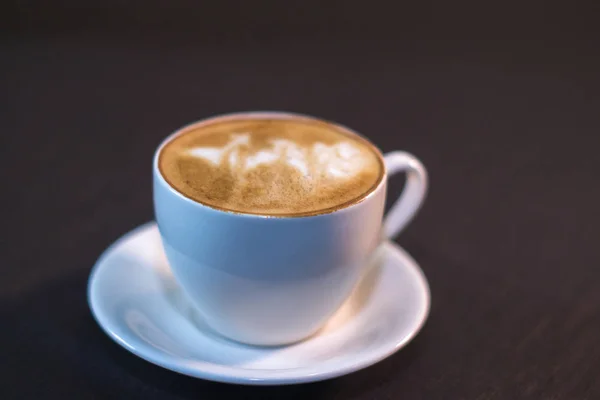 Uma xícara de café com uma foto em um café . — Fotografia de Stock