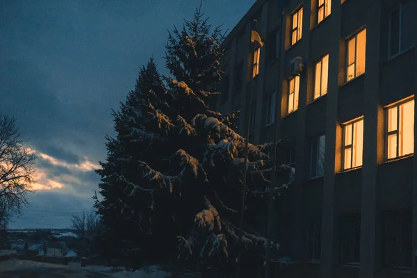 Światło z okien wieżowiec w wieczór zima śnieg. — Zdjęcie stockowe