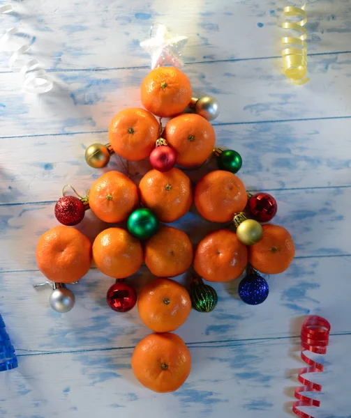 Beyaz zemin üzerinde bir mandalina ile Noel ağacı.