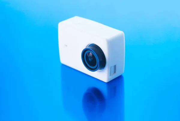 Action camera on a blue glossy background.