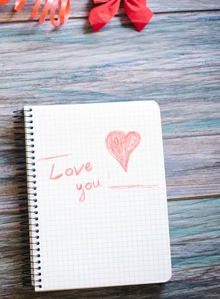 Inscripción Te amo en un bloc de notas blanco sobre un fondo de madera — Foto de Stock
