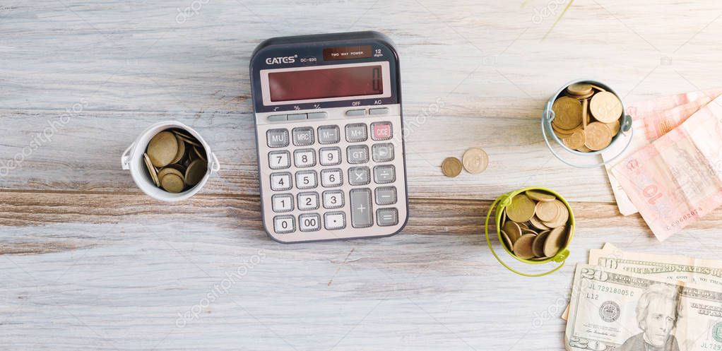 Calculator with money and pennies on a wooden green background. Business concept