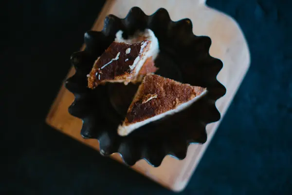 Ciasto na drewnianej tacy na czarnym tle matowy — Zdjęcie stockowe