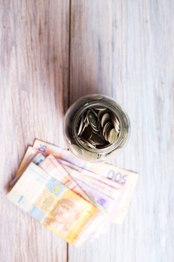 Ahşap arka plan üzerinde paralar ile Cam Kavanoz