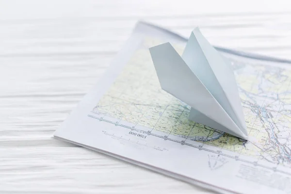 Paper airplane, on a map on a wooden background — Stock Photo, Image