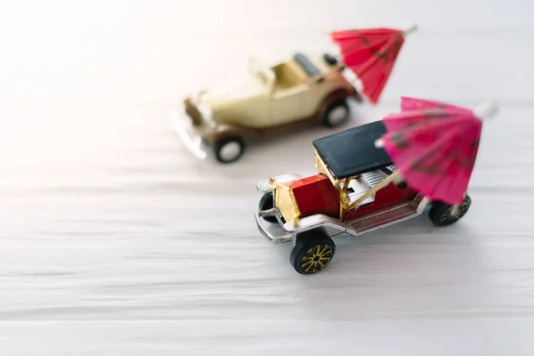 Two small toy cars with beach umbrellas. The concept of travel