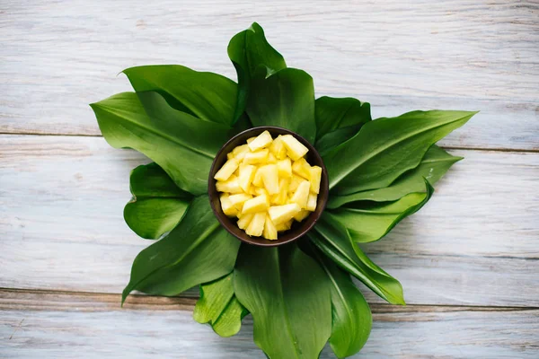 Taze ananas yaprakların üzerine bir kase dilimlenmiş