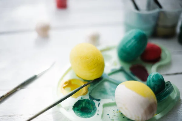 The process of painting Easter eggs still life on a white wooden background — Stock Photo, Image