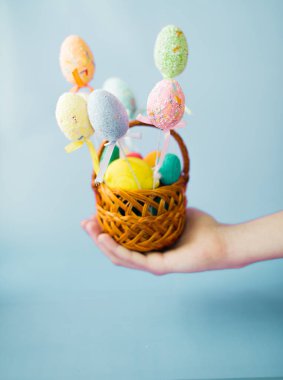 Paskalya yumurtaları el üzerinde mavi bir arka plan ile sepet