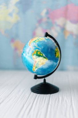 Bir ahşap beyaz masa arka planda bir dünya haritası üzerinde dünya.