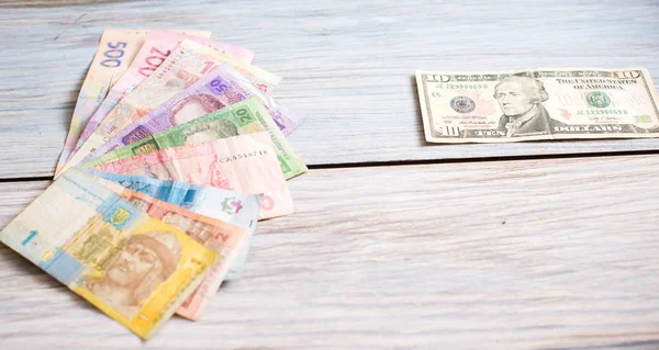Ukraynalı hryvnia ve ahşap arka plan üzerinde Amerikan Doları