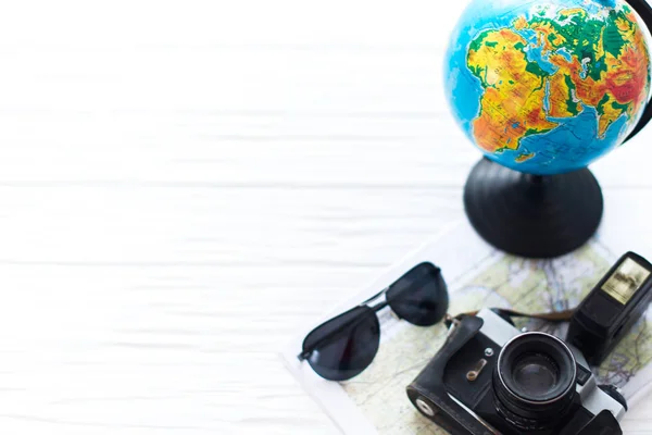 Uma câmera com um globo sobre um fundo de madeira branca. Kit do viajante — Fotografia de Stock