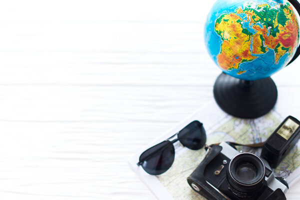 A camera with a globe on a white wooden background. Traveler's Kit.
