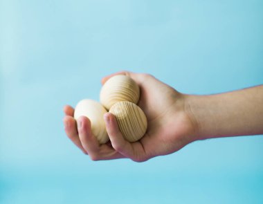 Mavi bir arka plan üzerinde elinde bir ahşap yumurta bir adam tutar