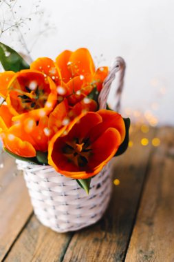 Çelenk içinde belgili tanımlık geçmiş ile ahşap arka plan üzerinde beyaz sepet içinde laleler