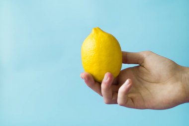 Bir adam bir limon mavi bir arka planda tutuyor