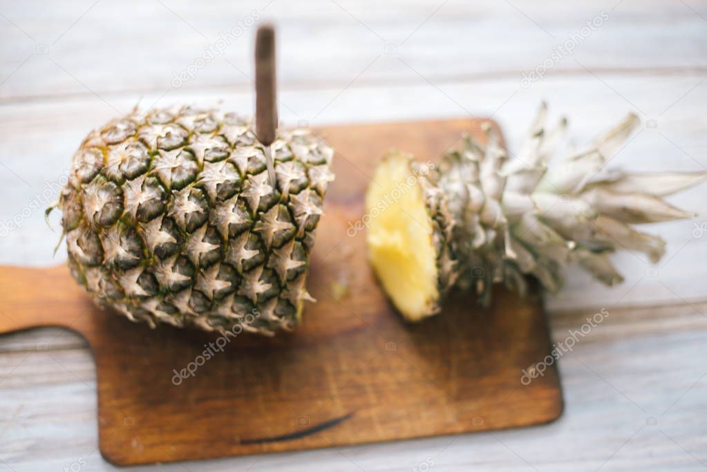 Ripe bisected ripe pineapple on a wooden background