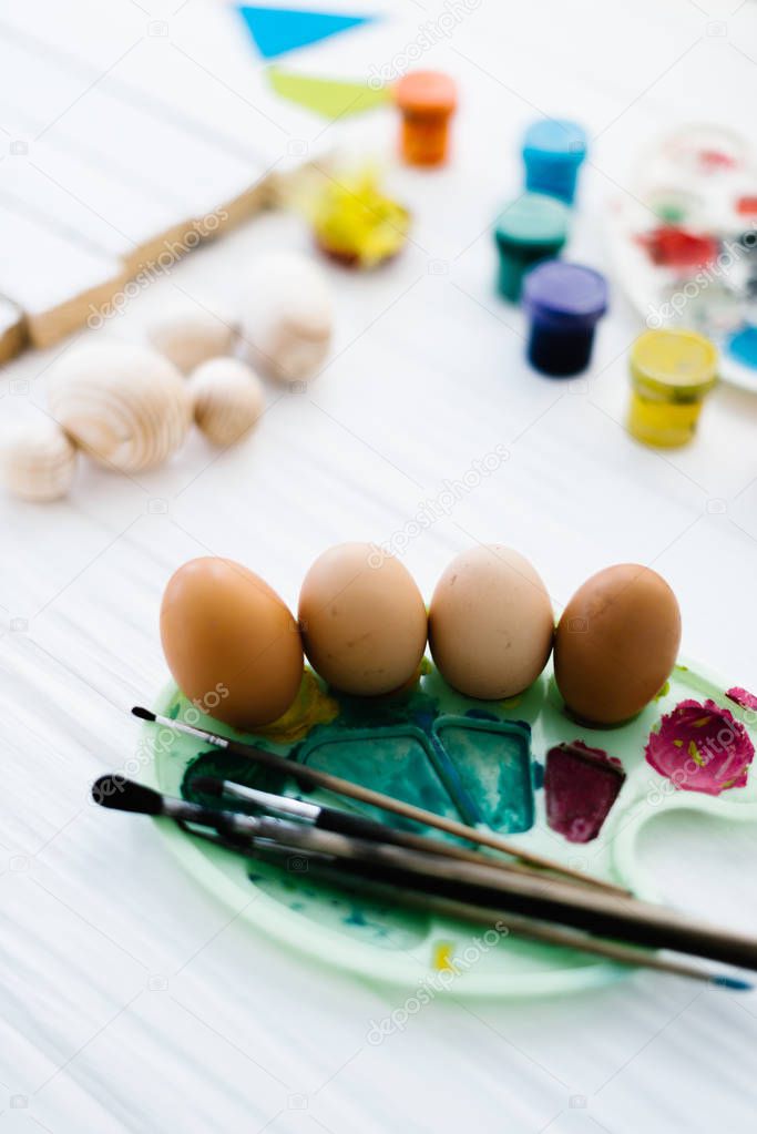 The process of painting Easter eggs still life on a white wooden background