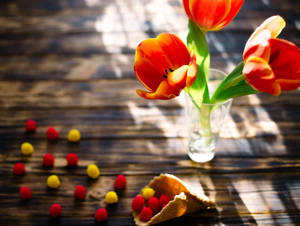 Цветущие красные тюльпаны на деревянном фоне со сладостями . — стоковое фото