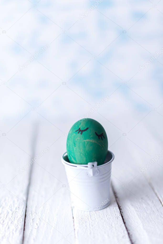 Easter eggs in a small bucket on a white blurred background.
