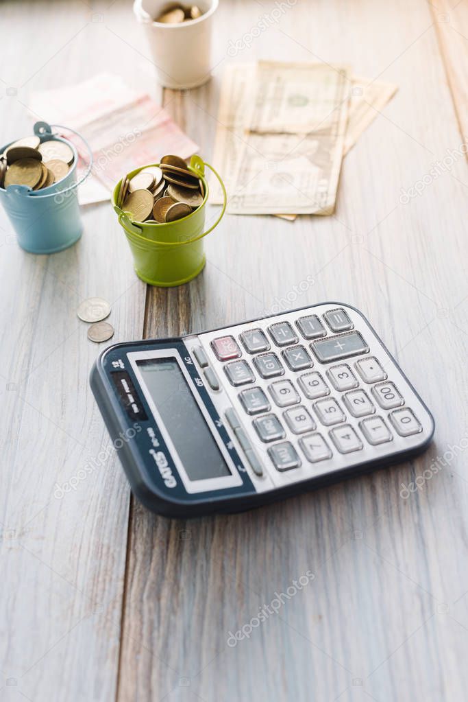 Calculator with money and pennies on a wooden green background. Business concept