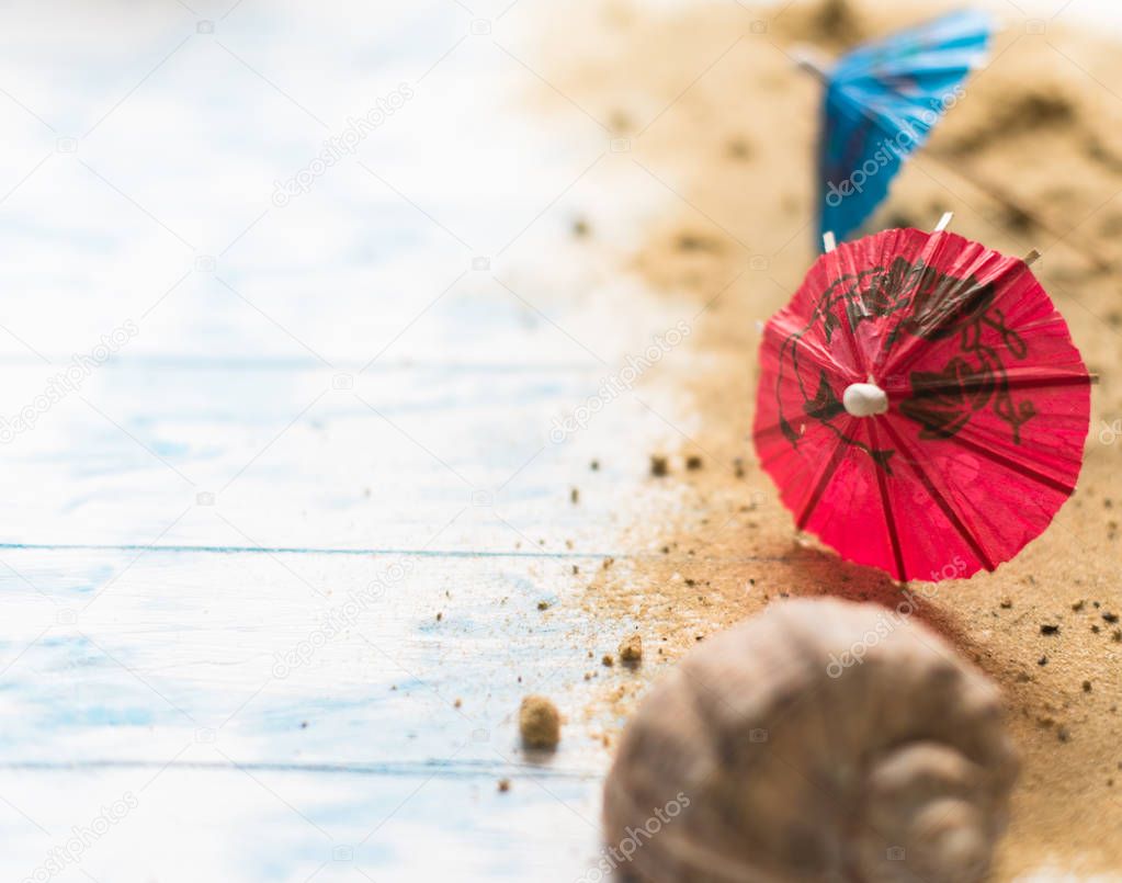 Beach summer background. Umbrellas on a pacifier on a wooden background with a shell