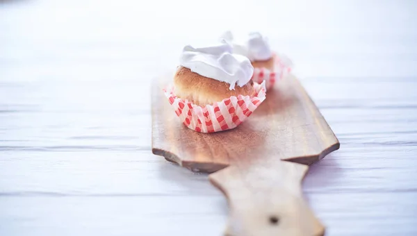 Cupcakes with white cream on a wooden background — Stock Photo, Image