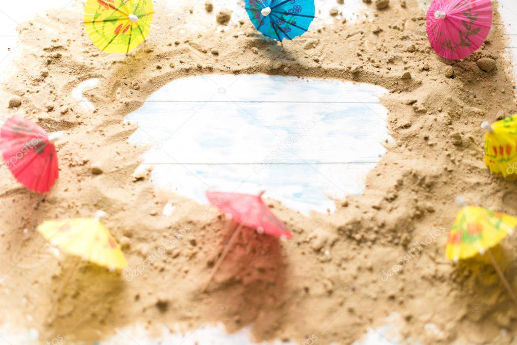 Summer background. Sand on a wooden board with beach umbrellas