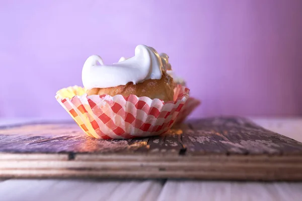 Cupcake with cream on a pastel background on a wooden table — Stock Photo, Image