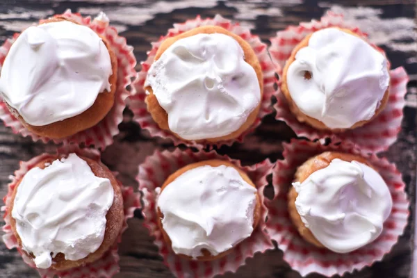 Pasteles con crema blanca sobre fondo de madera — Foto de Stock