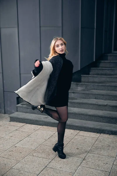 Girl in a black dress in the winter on a background of a dark building — Stock Photo, Image