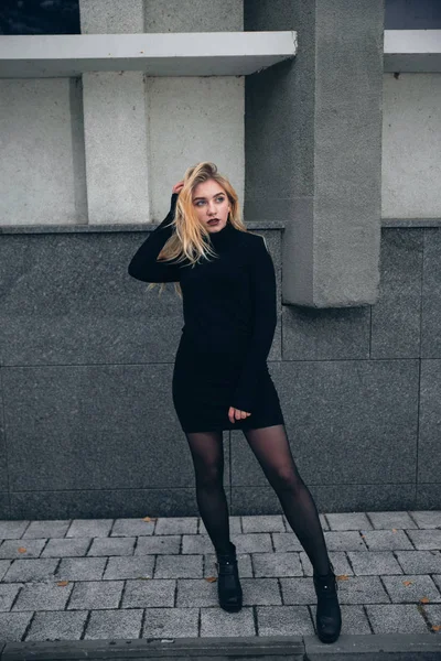 Dziewczyna w czarnej sukience w zimie na tle ciemnego budynku — Zdjęcie stockowe