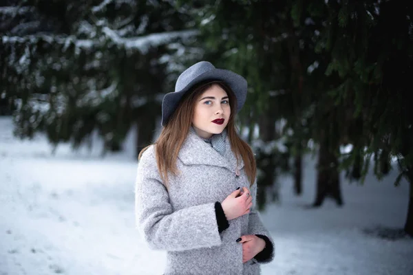 Flicka i grå rock i en snöpark på vintern — Stockfoto