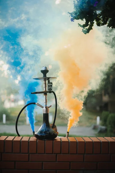 Hookah ao ar livre em um fundo de fumaça colorida — Fotografia de Stock