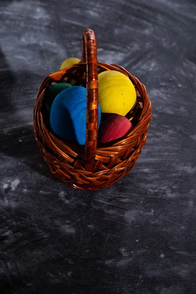 Uova multicolori pasquali in un cesto su sfondo scuro — Foto Stock