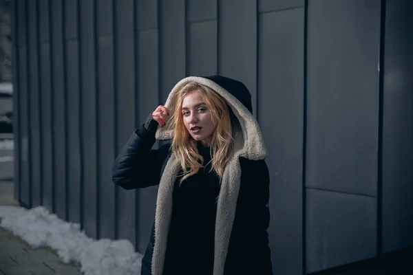 Girl in a black dress in the winter on a background of a dark building — Stock Photo, Image