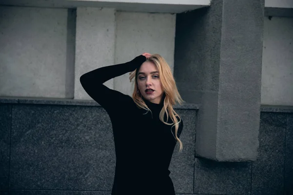 Girl in a black dress in the winter on a background of a dark building — Stock Photo, Image
